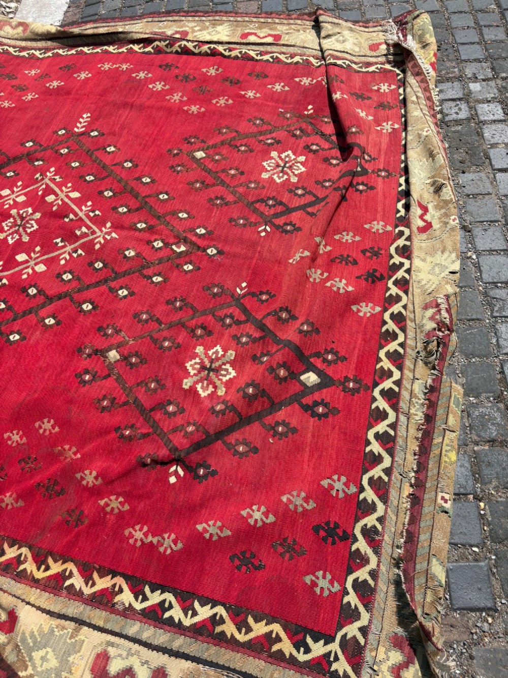 A large handwoven Anatolian flatweave kilim rug featuring a vivid red field patterned with dark geometric diamond motifs and framed by a light beige border. View XIV