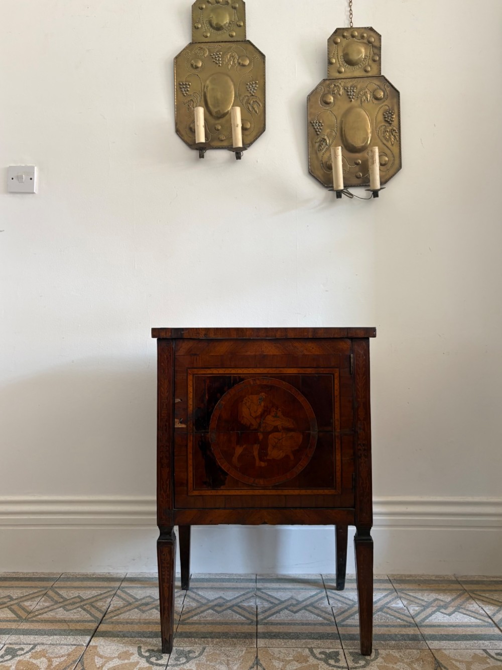 An 18th-century Italian Neoclassical walnut bedside cabinet featuring a central circular figurative marquetry panel on the front door, supported by square tapered legs. View VII