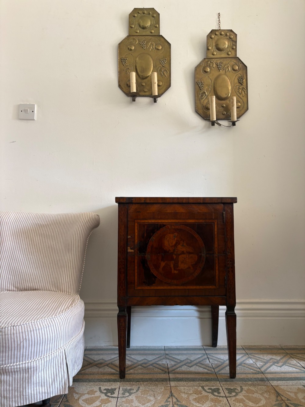 An 18th-century Italian Neoclassical walnut bedside cabinet featuring a central circular figurative marquetry panel on the front door, supported by square tapered legs. View X