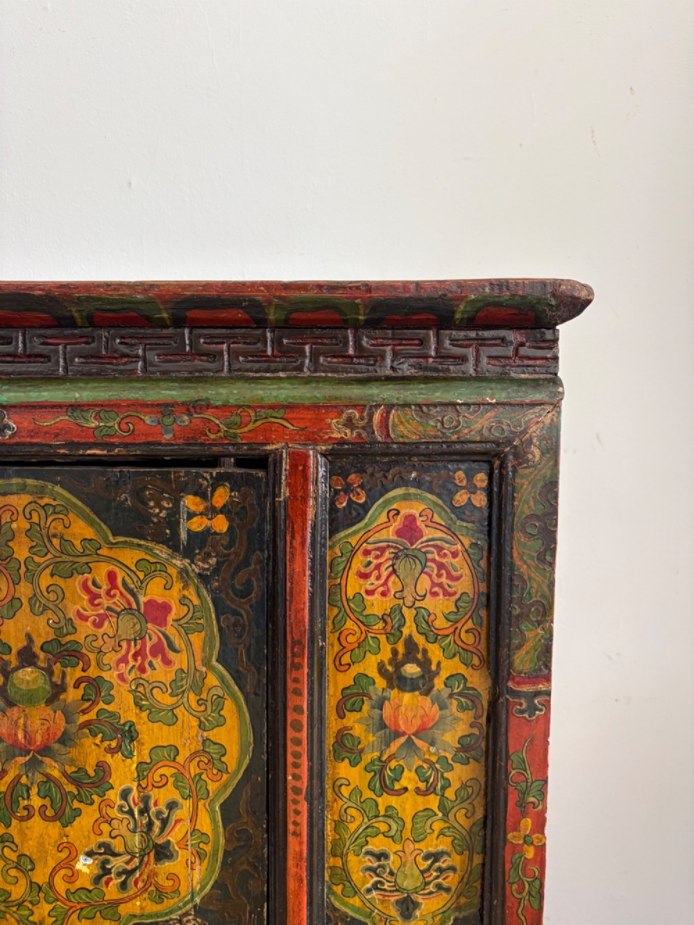 A 19th-century Tibetan wooden cabinet featuring four central hand-painted floral panels framed in red and gold mineral pigments. View XI