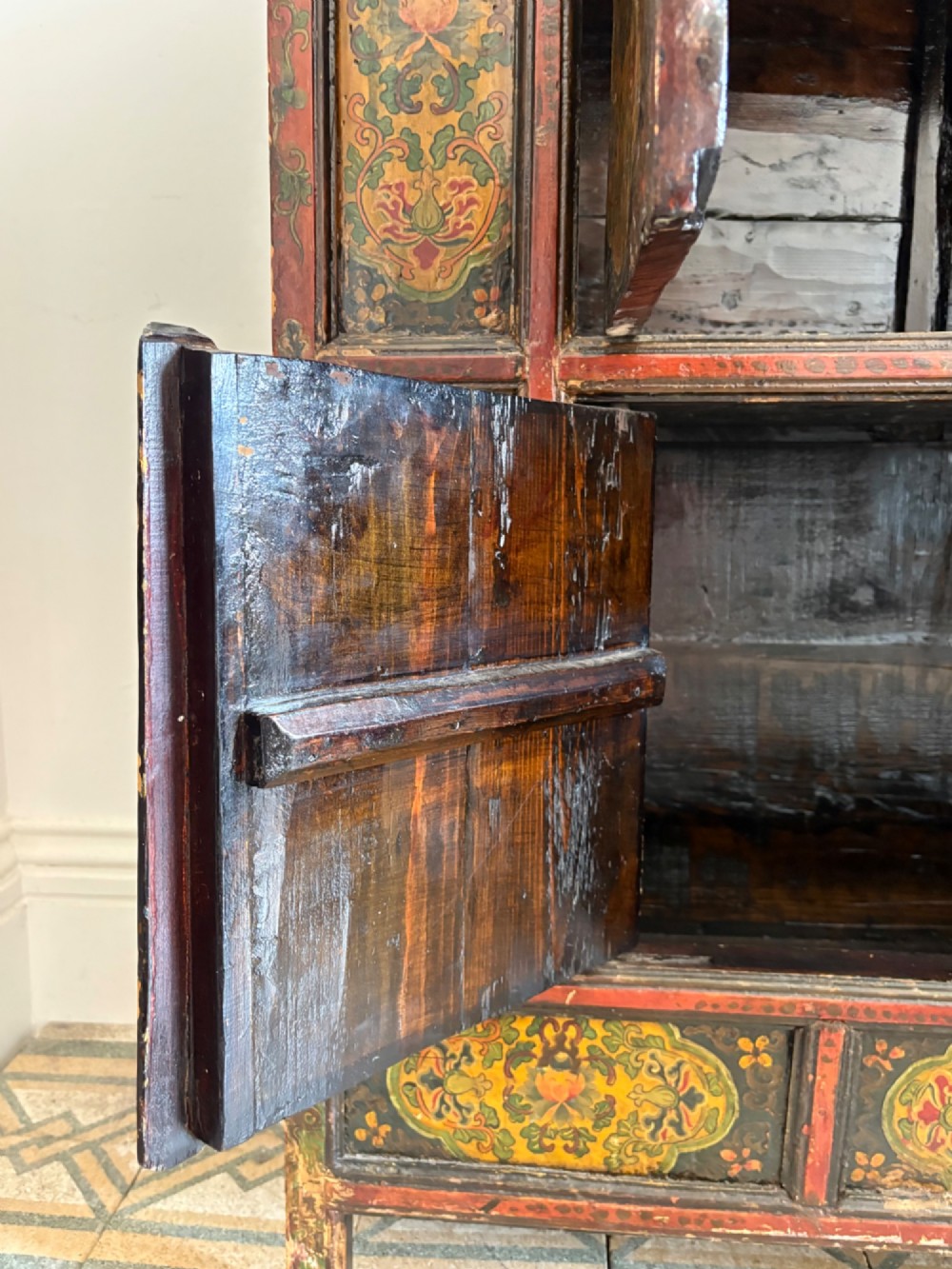 A 19th-century Tibetan wooden cabinet featuring four central hand-painted floral panels framed in red and gold mineral pigments. View XII
