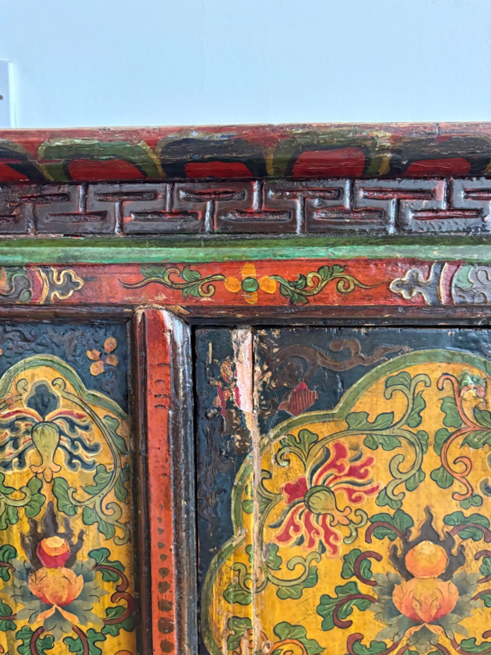 A 19th-century Tibetan wooden cabinet featuring four central hand-painted floral panels framed in red and gold mineral pigments. View XIV