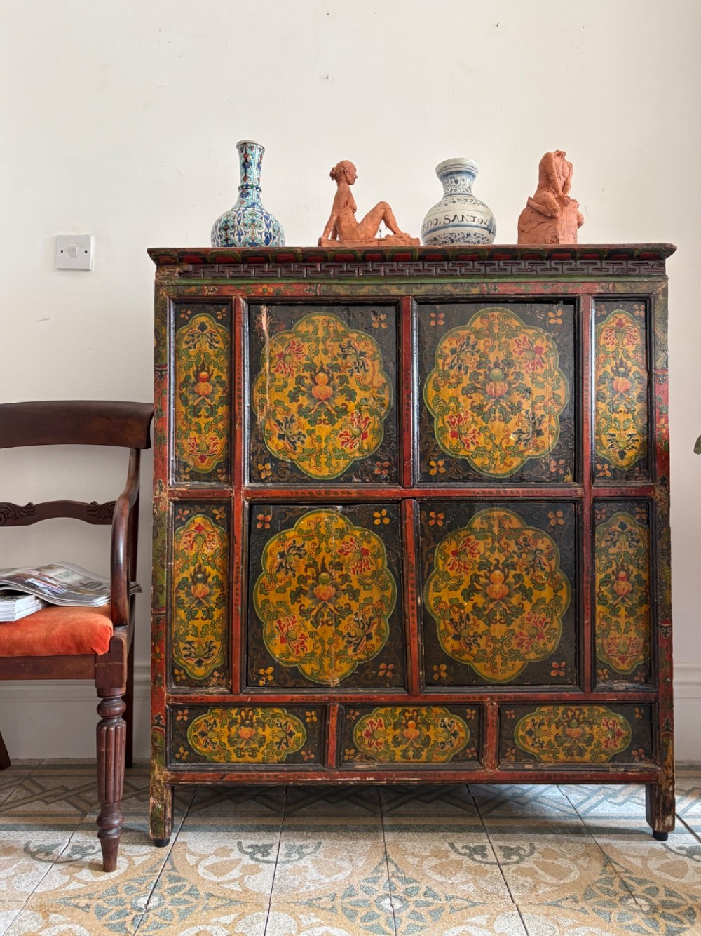 A 19th-century Tibetan wooden cabinet featuring four central hand-painted floral panels framed in red and gold mineral pigments. View XV