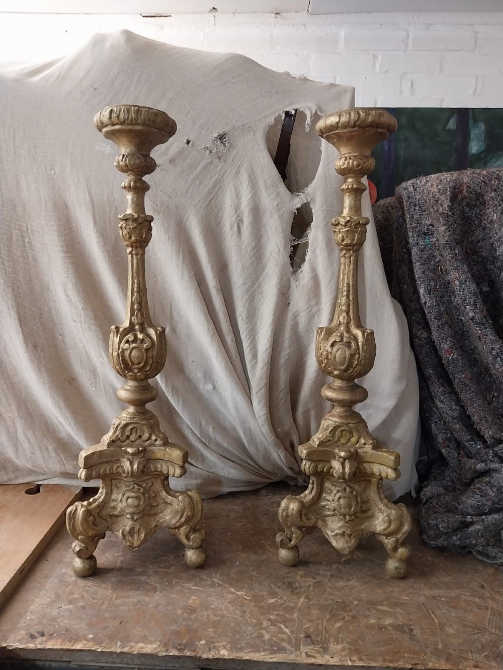 A pair of 18th-century Italian Baroque carved giltwood altar candlesticks featuring triform bases with scrollwork and tall baluster stems. View II