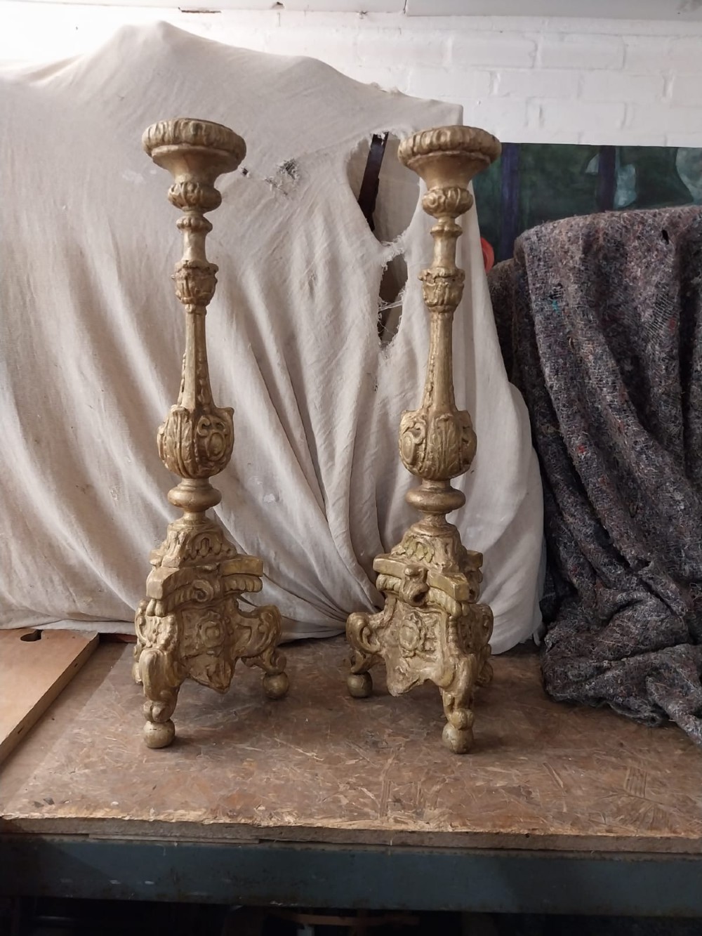 A pair of 18th-century Italian Baroque carved giltwood altar candlesticks featuring triform bases with scrollwork and tall baluster stems. View III