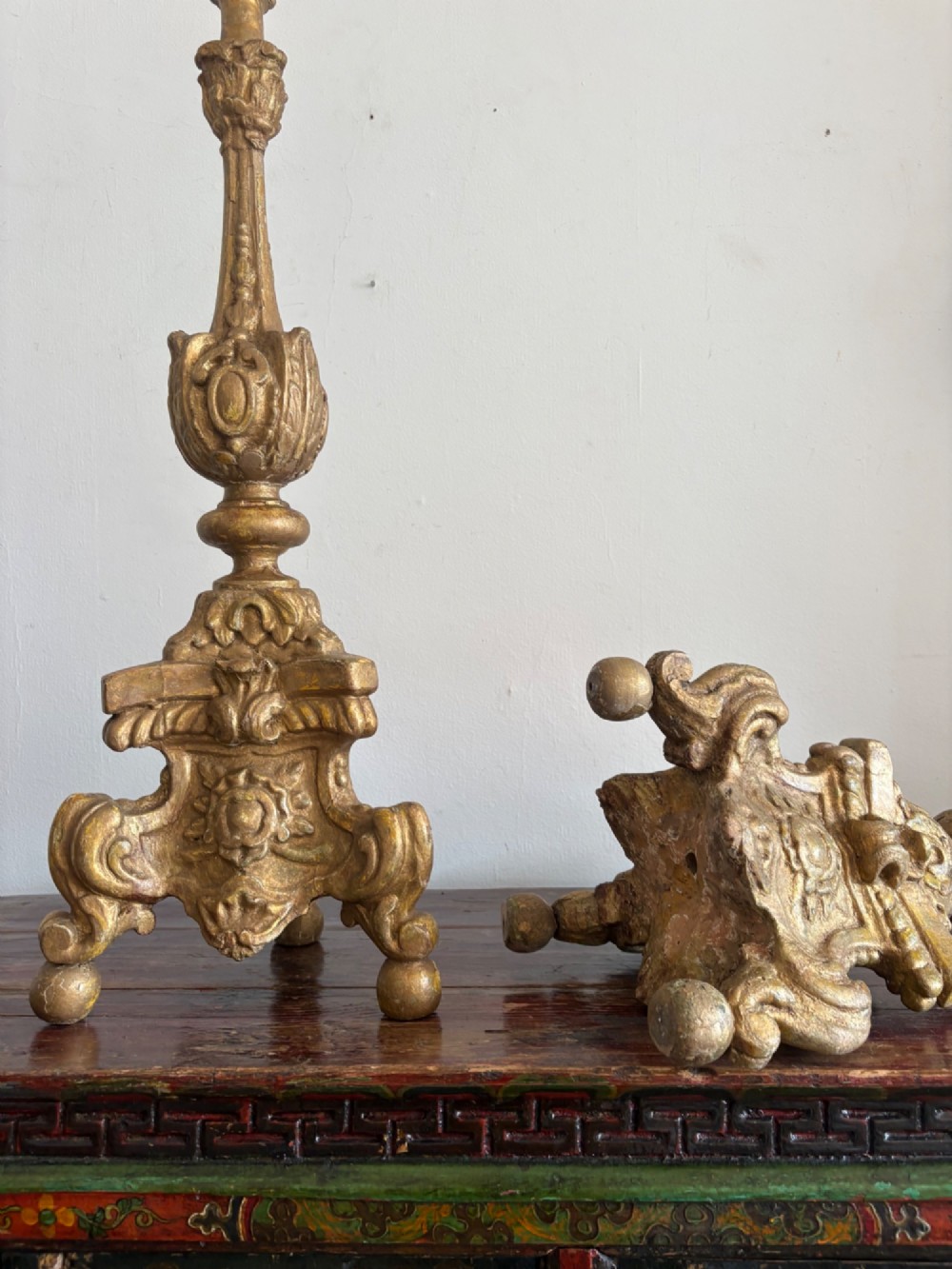 A pair of 18th-century Italian Baroque carved giltwood altar candlesticks featuring triform bases with scrollwork and tall baluster stems. View V