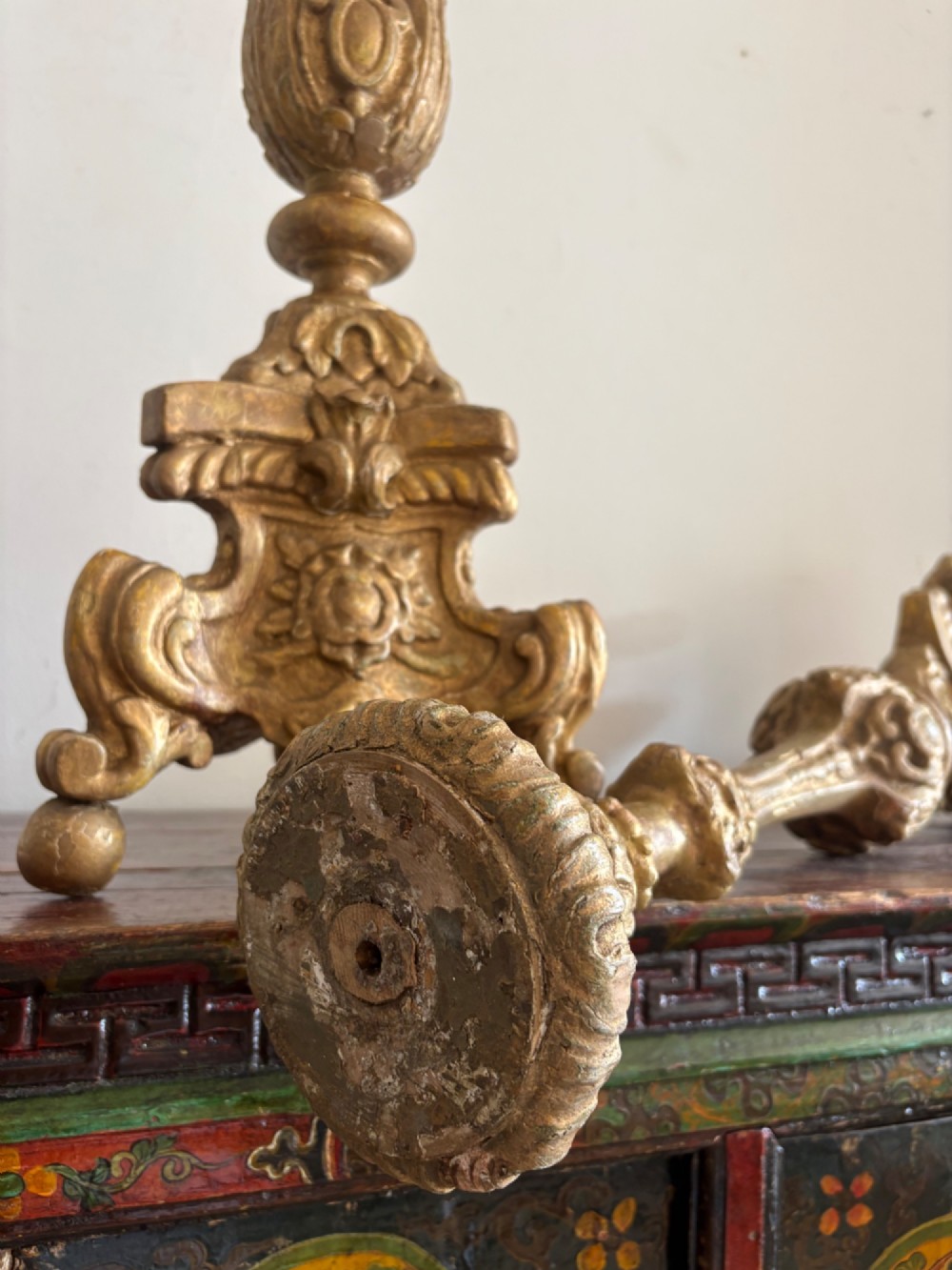 A pair of 18th-century Italian Baroque carved giltwood altar candlesticks featuring triform bases with scrollwork and tall baluster stems. View VI