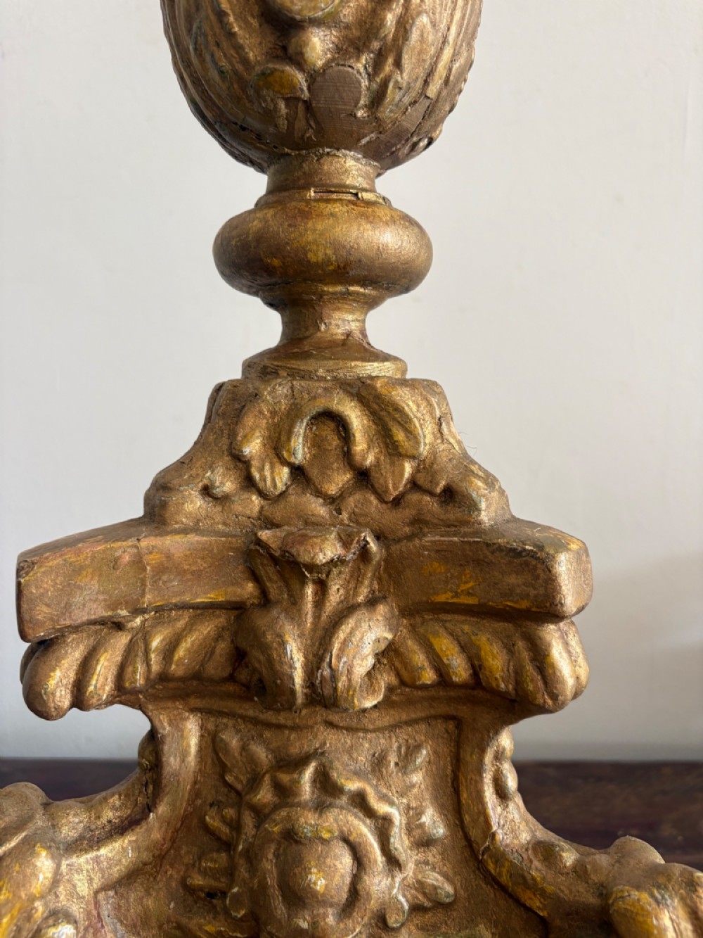 A pair of 18th-century Italian Baroque carved giltwood altar candlesticks featuring triform bases with scrollwork and tall baluster stems. View VII