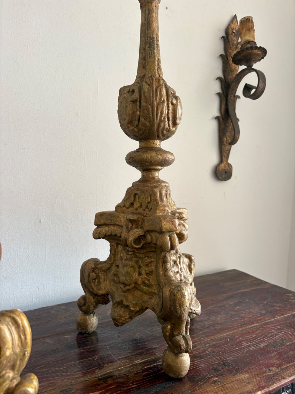 A pair of 18th-century Italian Baroque carved giltwood altar candlesticks featuring triform bases with scrollwork and tall baluster stems. View VIII