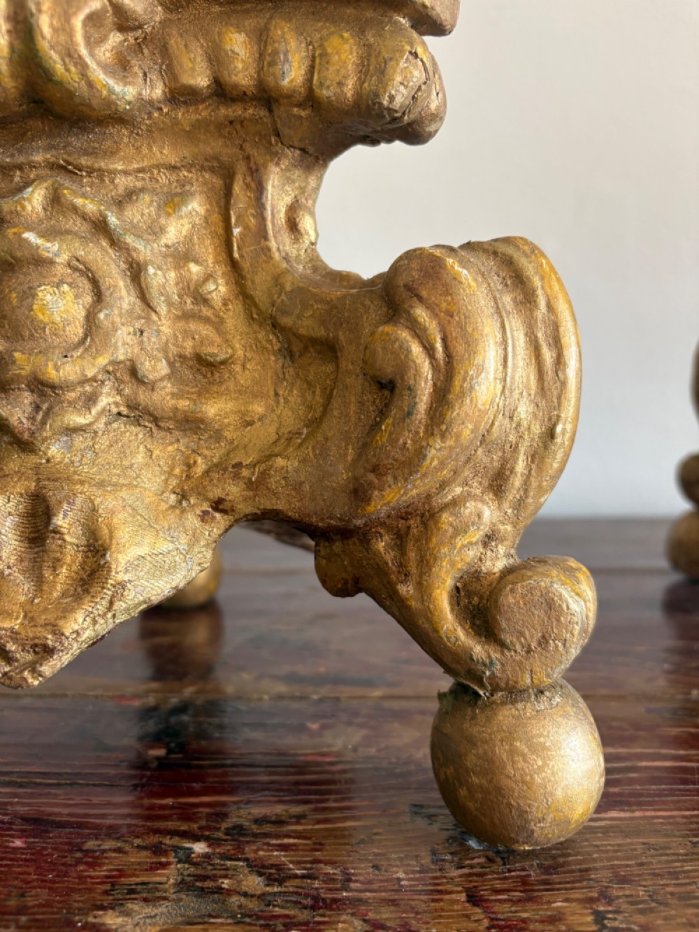A pair of 18th-century Italian Baroque carved giltwood altar candlesticks featuring triform bases with scrollwork and tall baluster stems. View X