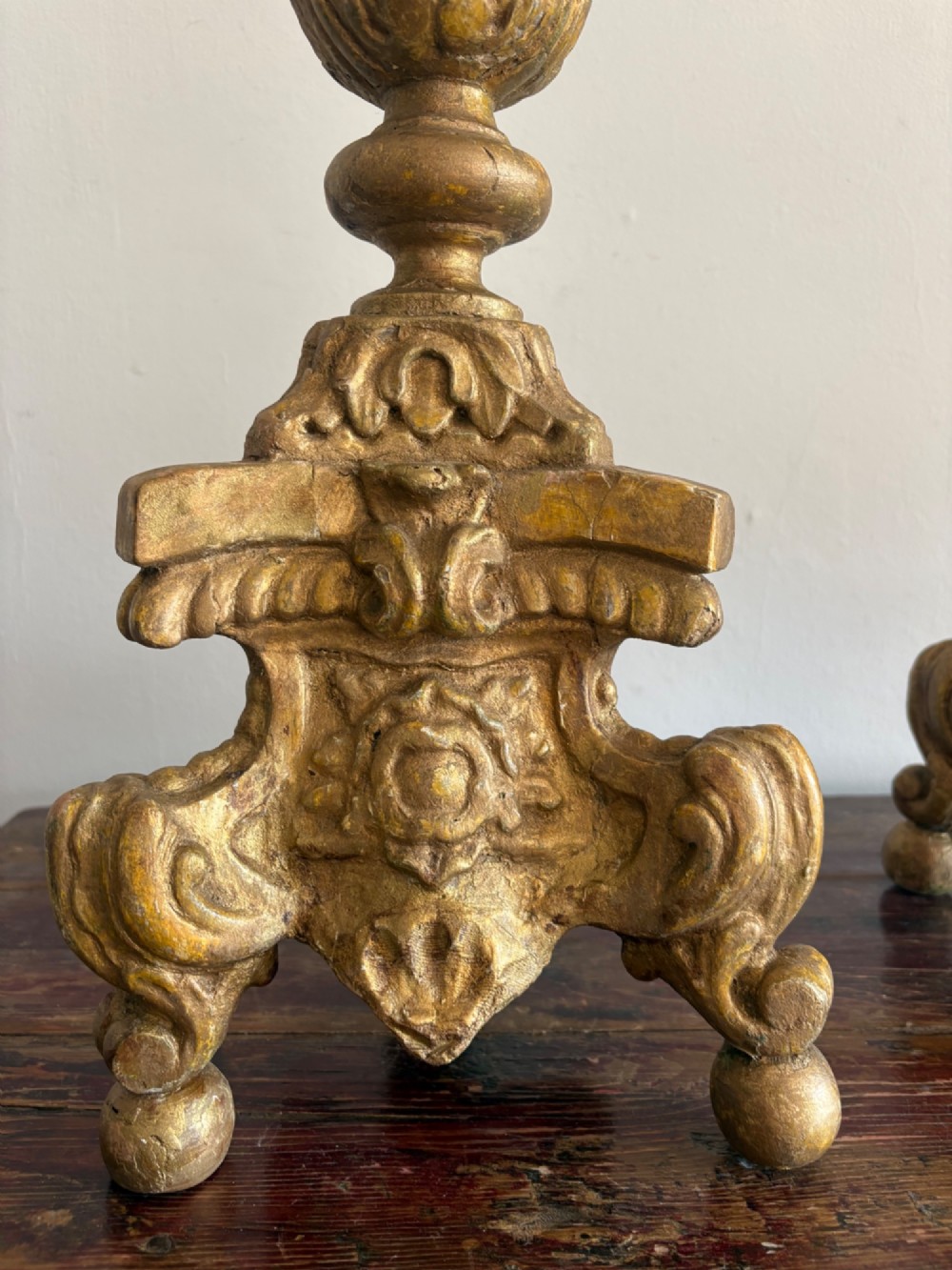 A pair of 18th-century Italian Baroque carved giltwood altar candlesticks featuring triform bases with scrollwork and tall baluster stems. View XI