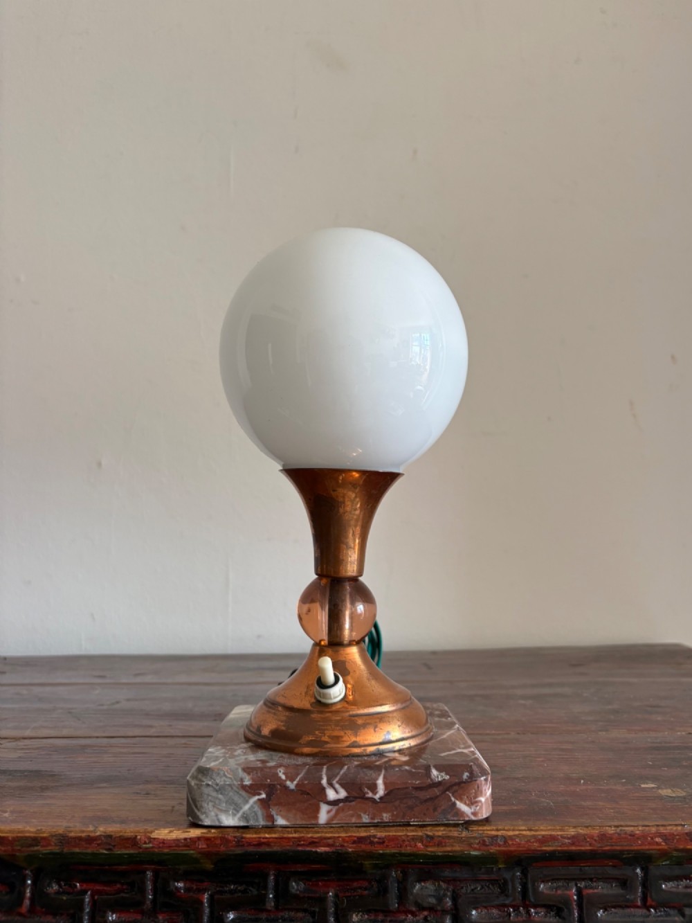 A small French Art Deco table lamp featuring a spherical white opaline glass shade atop a turned copper stem mounted on a square veined marble base.