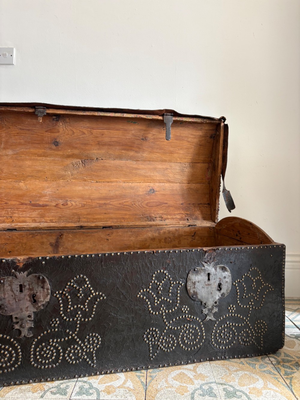 An 18th-century Dutch dark brown leather trunk featuring a domed lid, intricate brass studding in scrolling floral patterns, and iron lock hardware. View III
