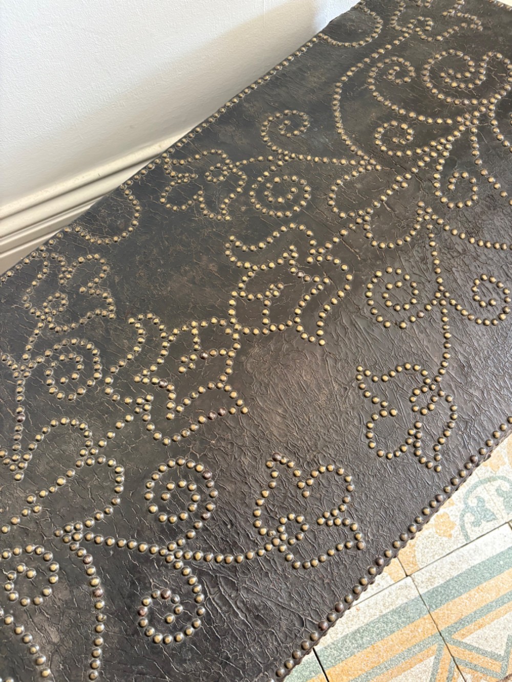 An 18th-century Dutch dark brown leather trunk featuring a domed lid, intricate brass studding in scrolling floral patterns, and iron lock hardware. View V