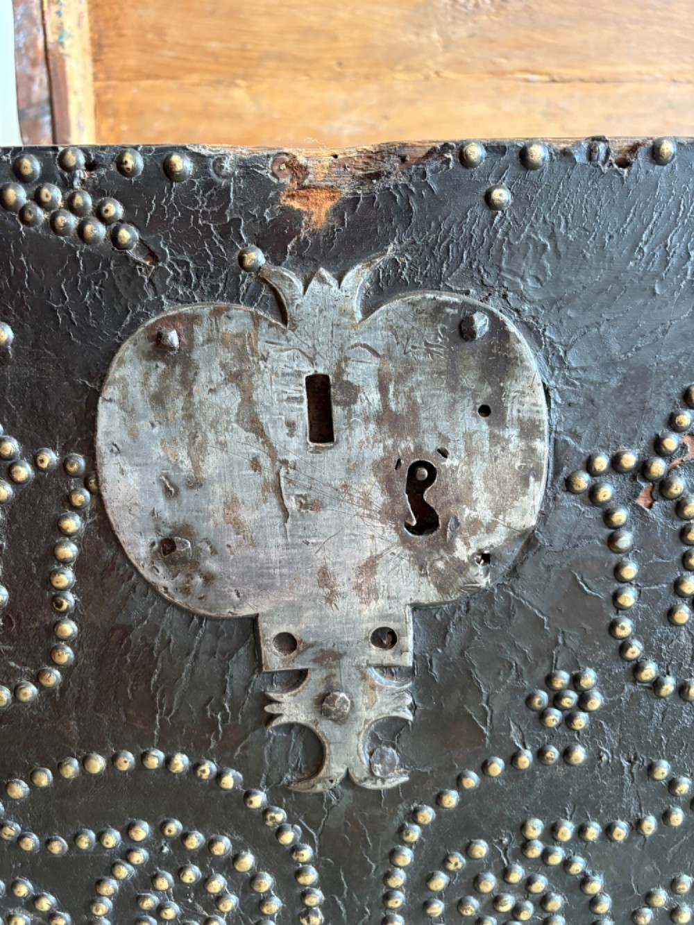 An 18th-century Dutch dark brown leather trunk featuring a domed lid, intricate brass studding in scrolling floral patterns, and iron lock hardware. View VII