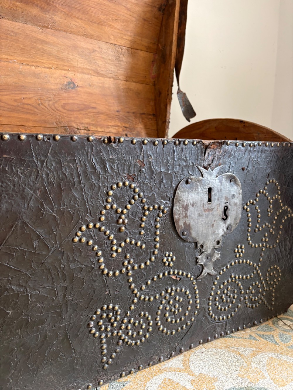 An 18th-century Dutch dark brown leather trunk featuring a domed lid, intricate brass studding in scrolling floral patterns, and iron lock hardware. View IX