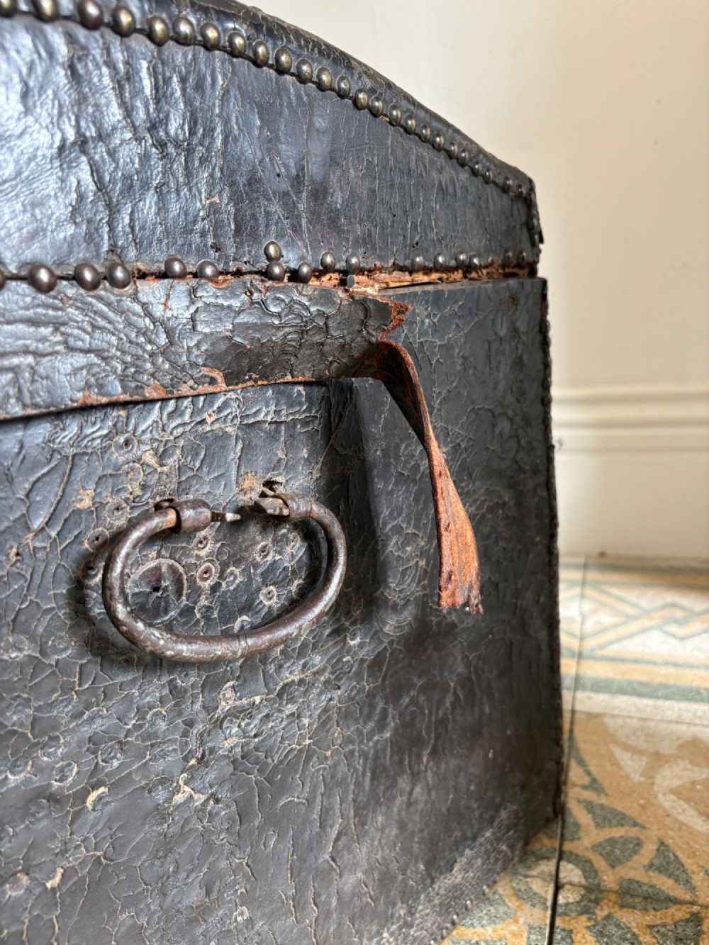 An 18th-century Dutch dark brown leather trunk featuring a domed lid, intricate brass studding in scrolling floral patterns, and iron lock hardware. View XII