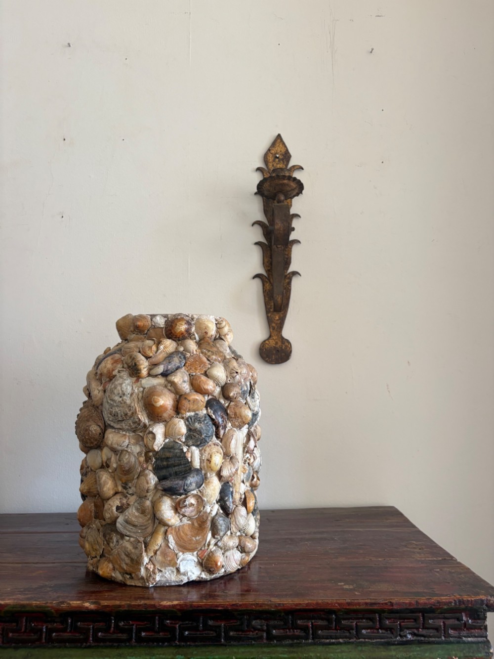 A cylindrical antique vase completely encrusted with an assortment of natural sea shells set into a mortar matrix. View II