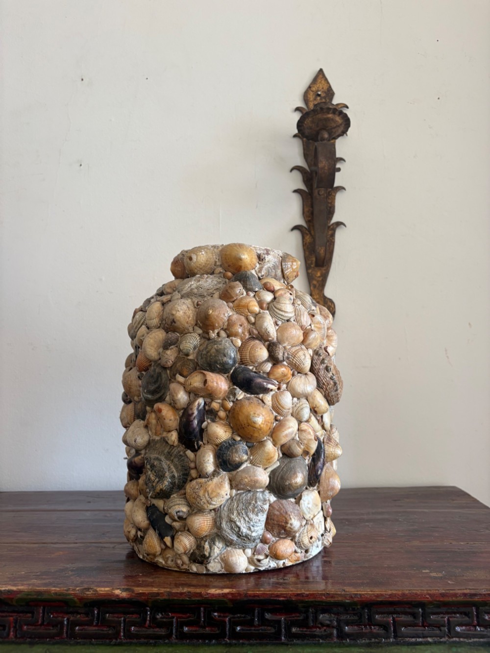 A cylindrical antique vase completely encrusted with an assortment of natural sea shells set into a mortar matrix. View III
