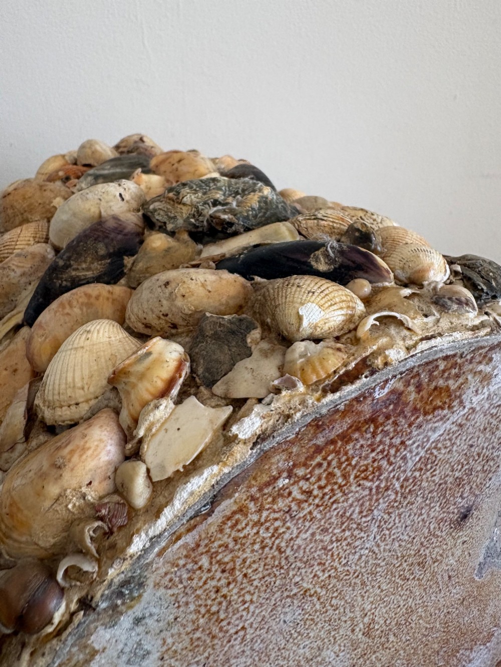 A cylindrical antique vase completely encrusted with an assortment of natural sea shells set into a mortar matrix. View V