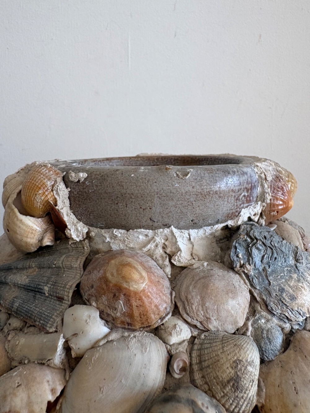 A cylindrical antique vase completely encrusted with an assortment of natural sea shells set into a mortar matrix. View X