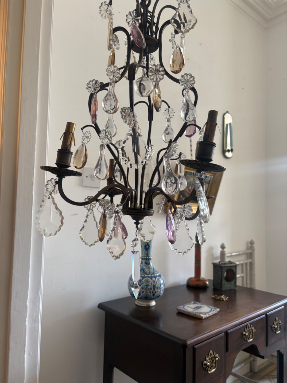 A four-branch French Rococo style gilt bronze chandelier decorated with clear, grey, and violet crystal drops. View II