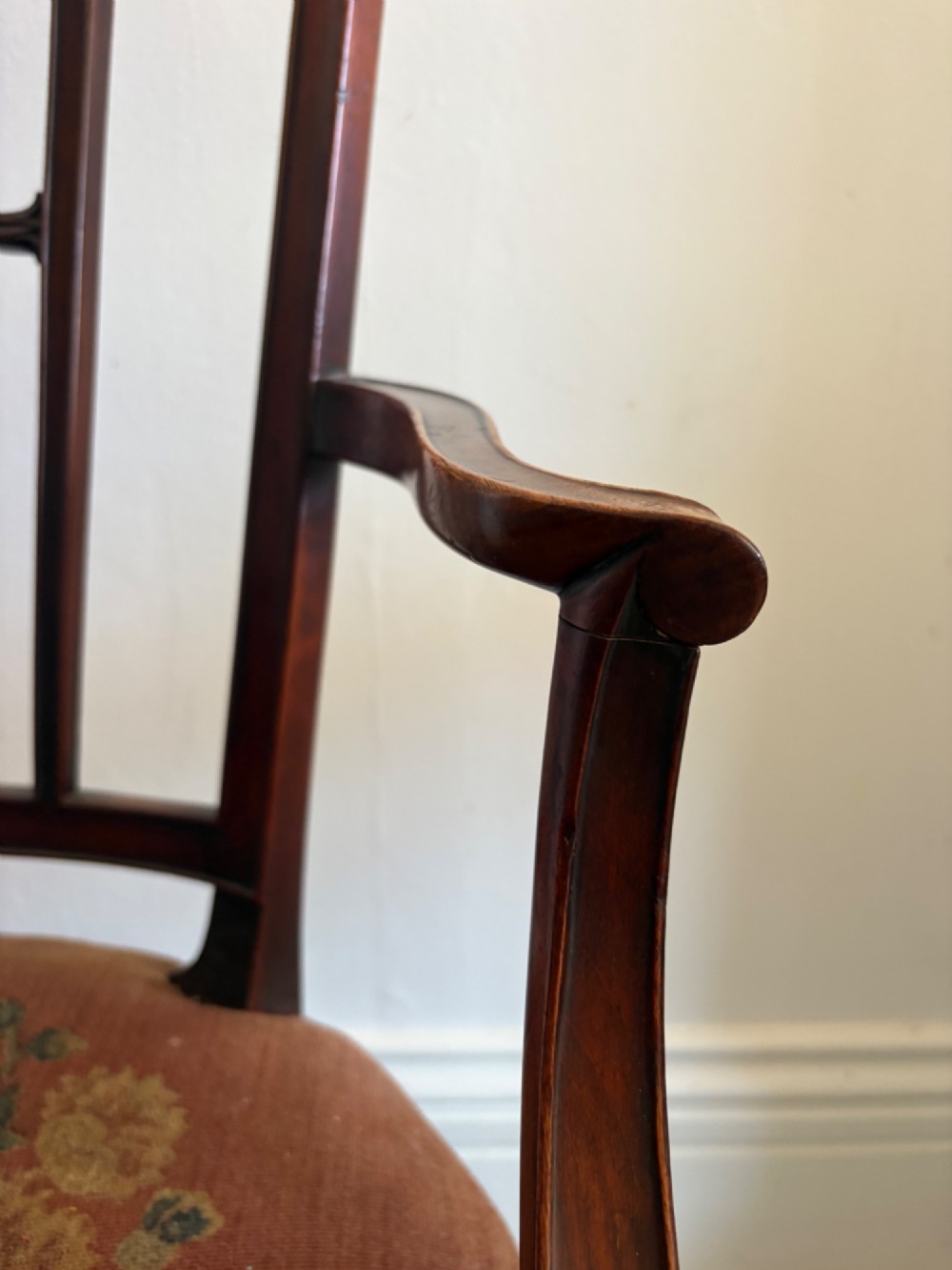 A late 18th-century Georgian mahogany open armchair featuring a carved back splat with a central rosewood roundel, swept armrests, and reddish-brown fabric upholstery. View XII
