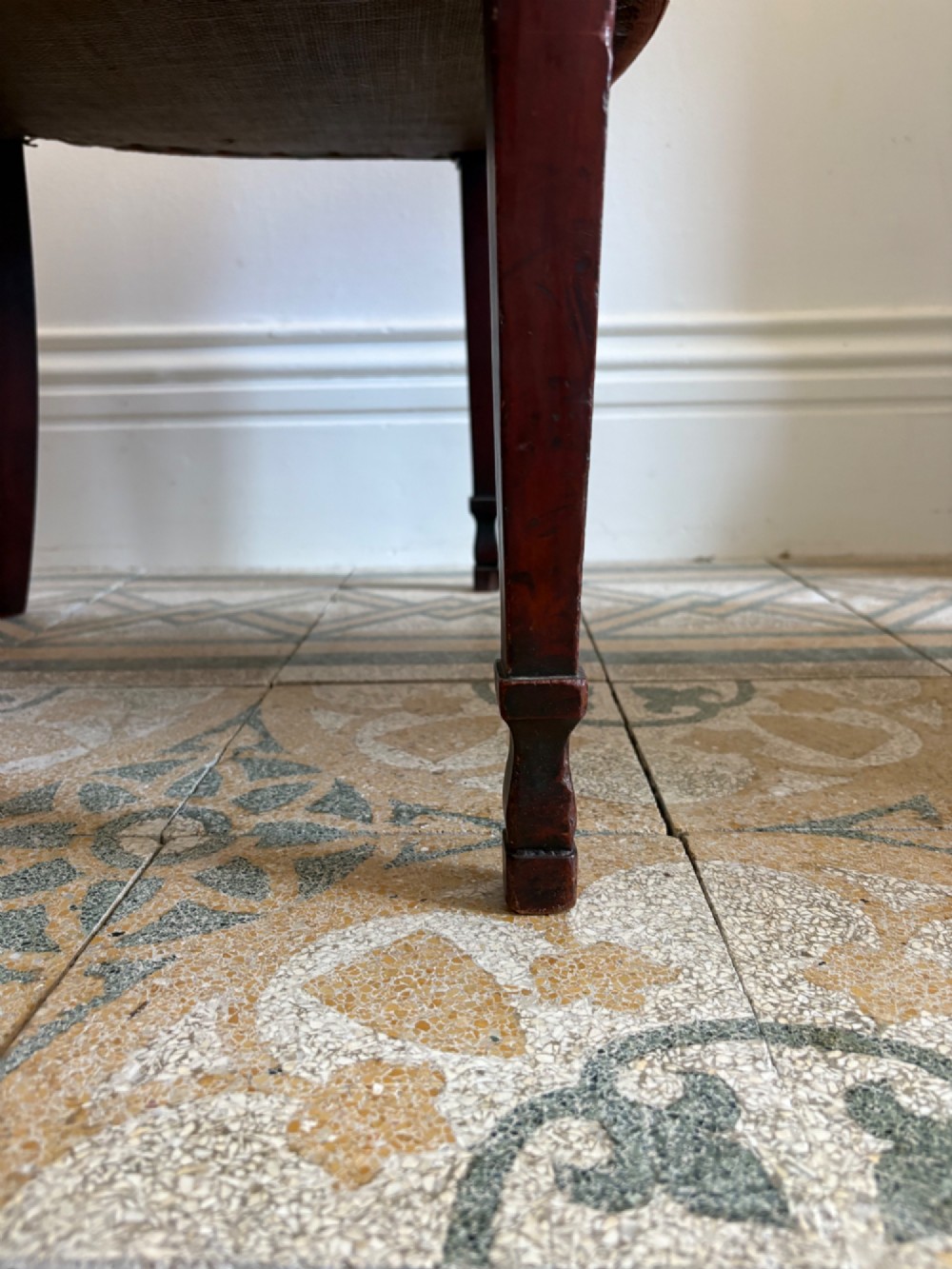 A late 18th-century Georgian mahogany open armchair featuring a carved back splat with a central rosewood roundel, swept armrests, and reddish-brown fabric upholstery. View XIII
