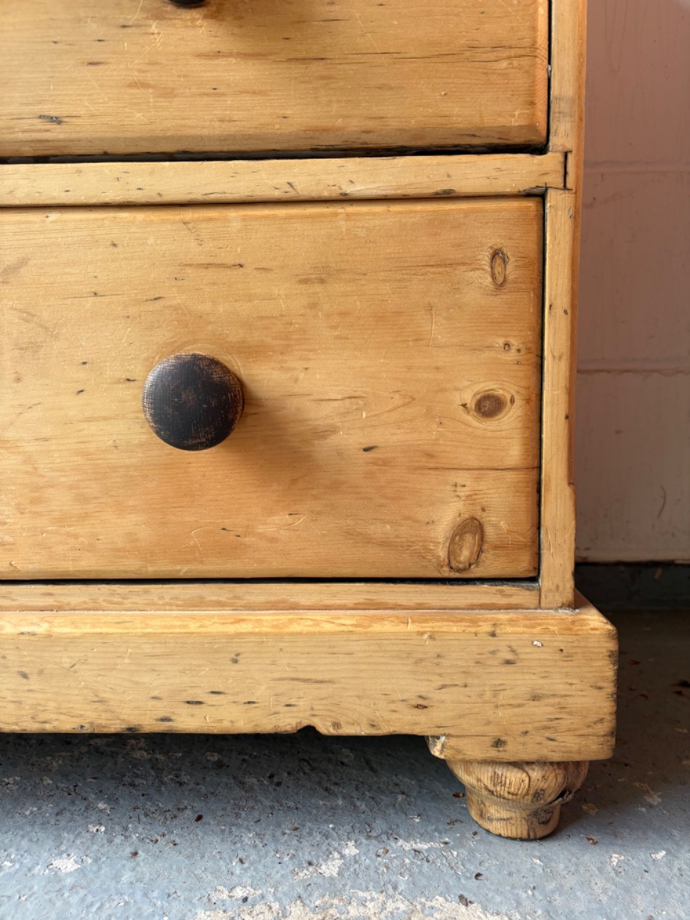 A nineteenth-century scrubbed pine chest of drawers with two small drawers above two long drawers featuring dark turned bun handles. View VI