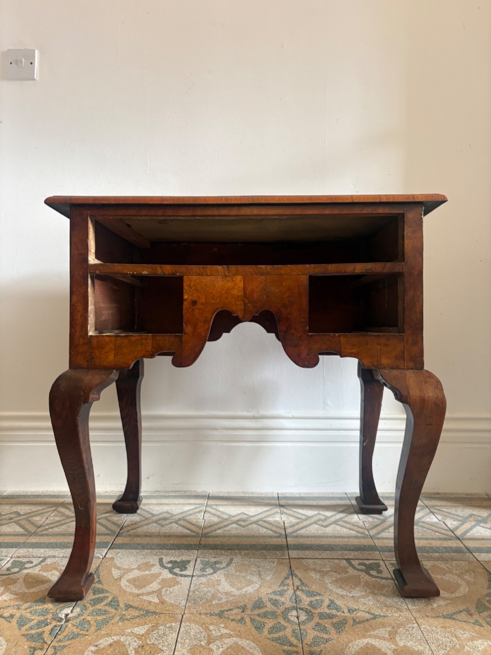 An early 18th-century figured walnut lowboy side table featuring three drawers, a shaped apron, brass handles, and cabriole legs. View XI