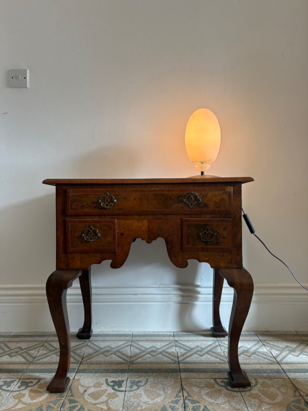 An early 18th-century figured walnut lowboy side table featuring three drawers, a shaped apron, brass handles, and cabriole legs. View XIV