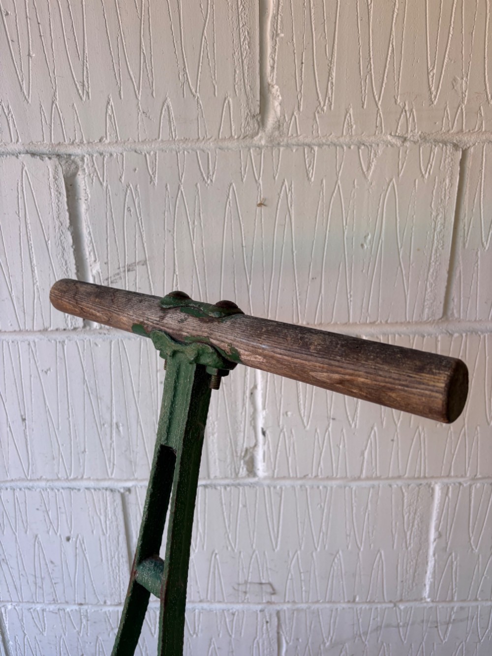 An antique cast iron garden roller featuring a green painted openwork frame with circular crest, a split drum cylinder, and a wooden handle bar. View VI