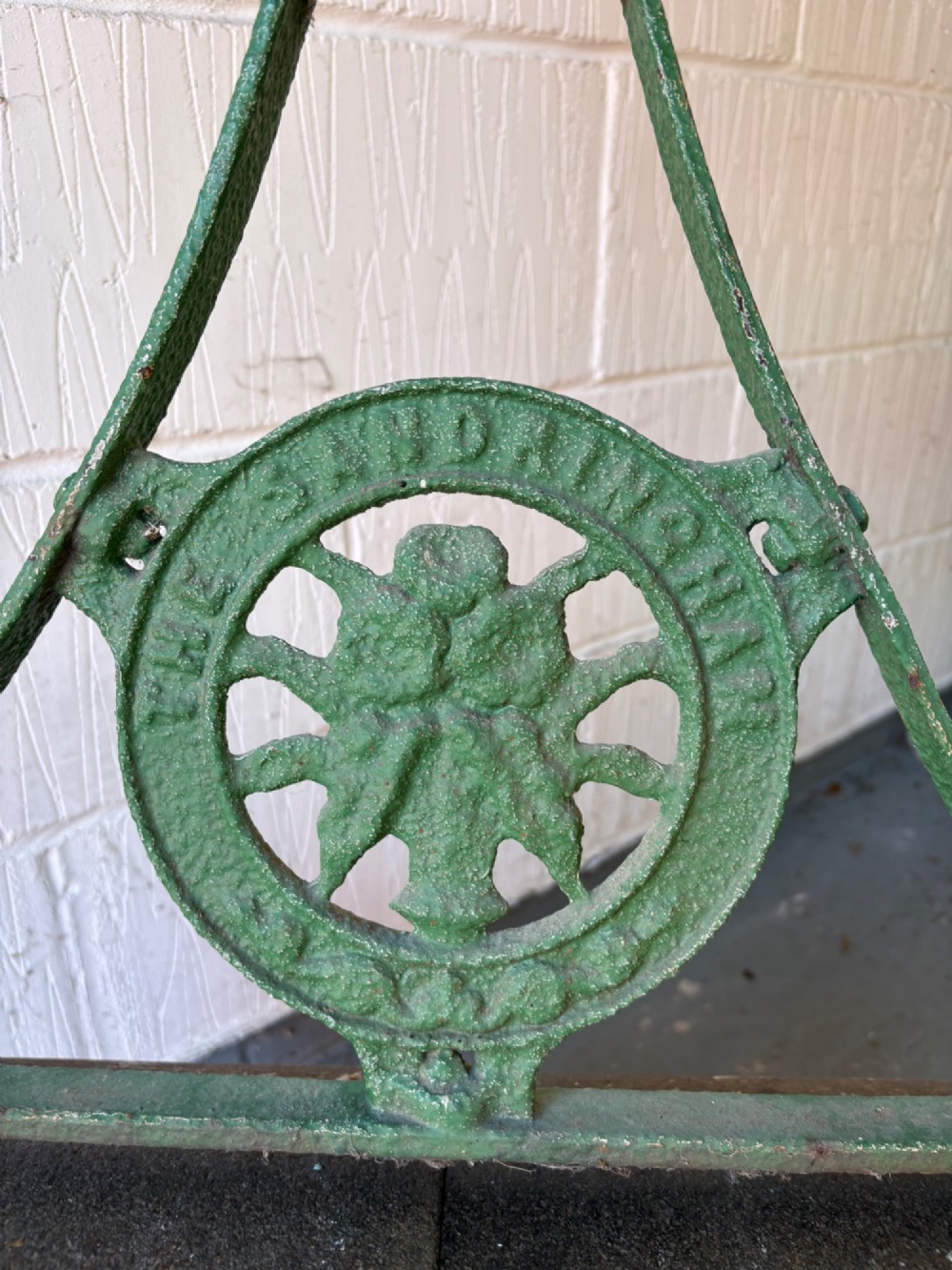 An antique cast iron garden roller featuring a green painted openwork frame with circular crest, a split drum cylinder, and a wooden handle bar. View VIII