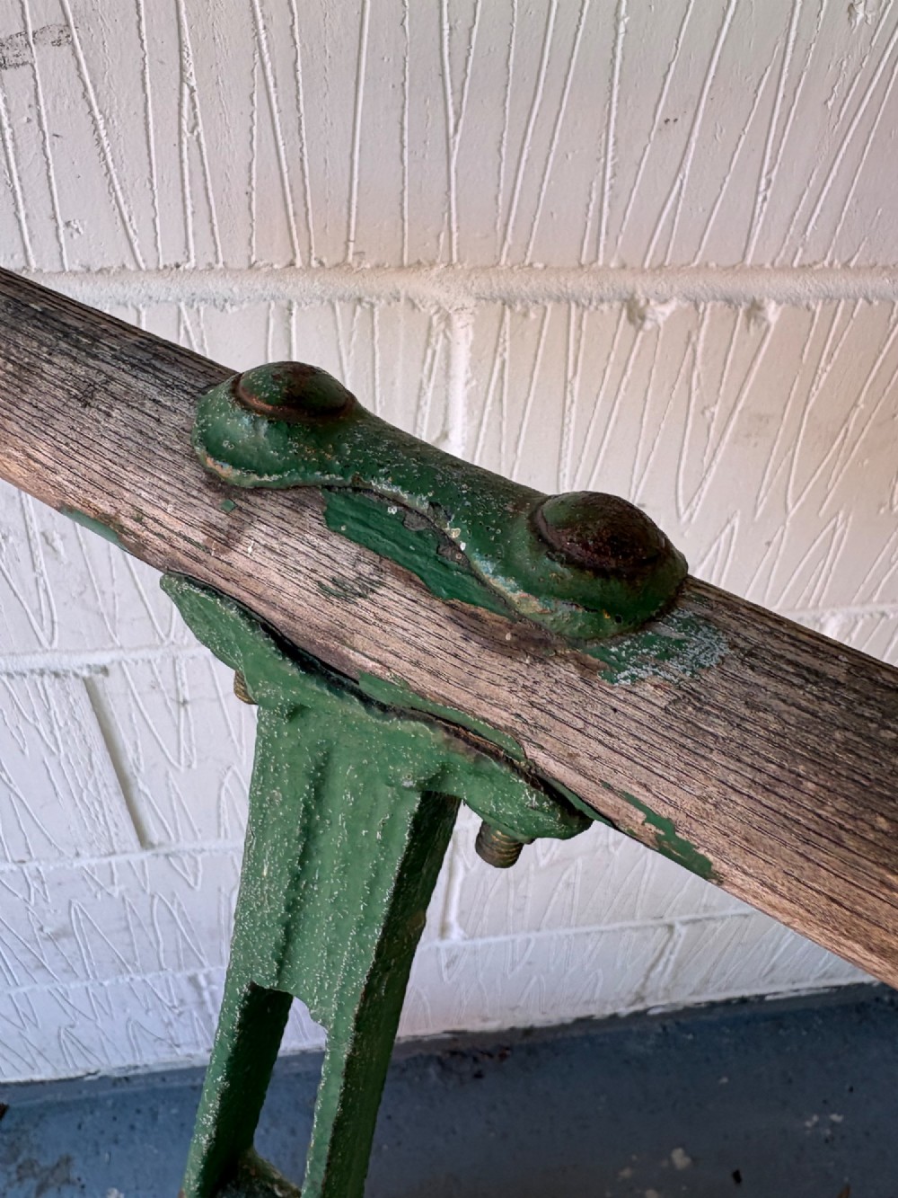 An antique cast iron garden roller featuring a green painted openwork frame with circular crest, a split drum cylinder, and a wooden handle bar. View IX