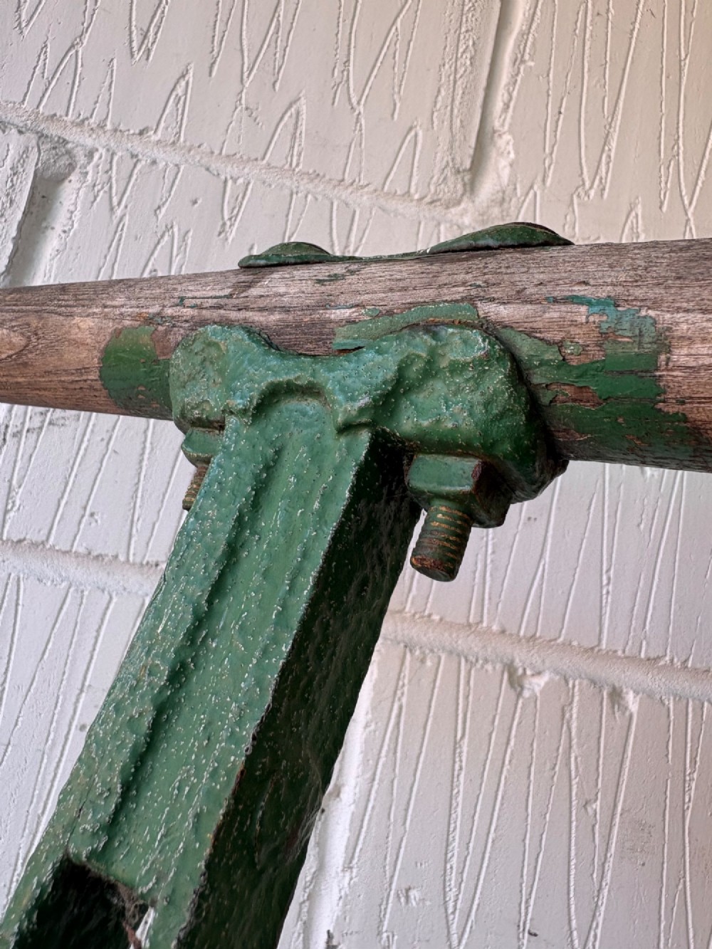 An antique cast iron garden roller featuring a green painted openwork frame with circular crest, a split drum cylinder, and a wooden handle bar. View X
