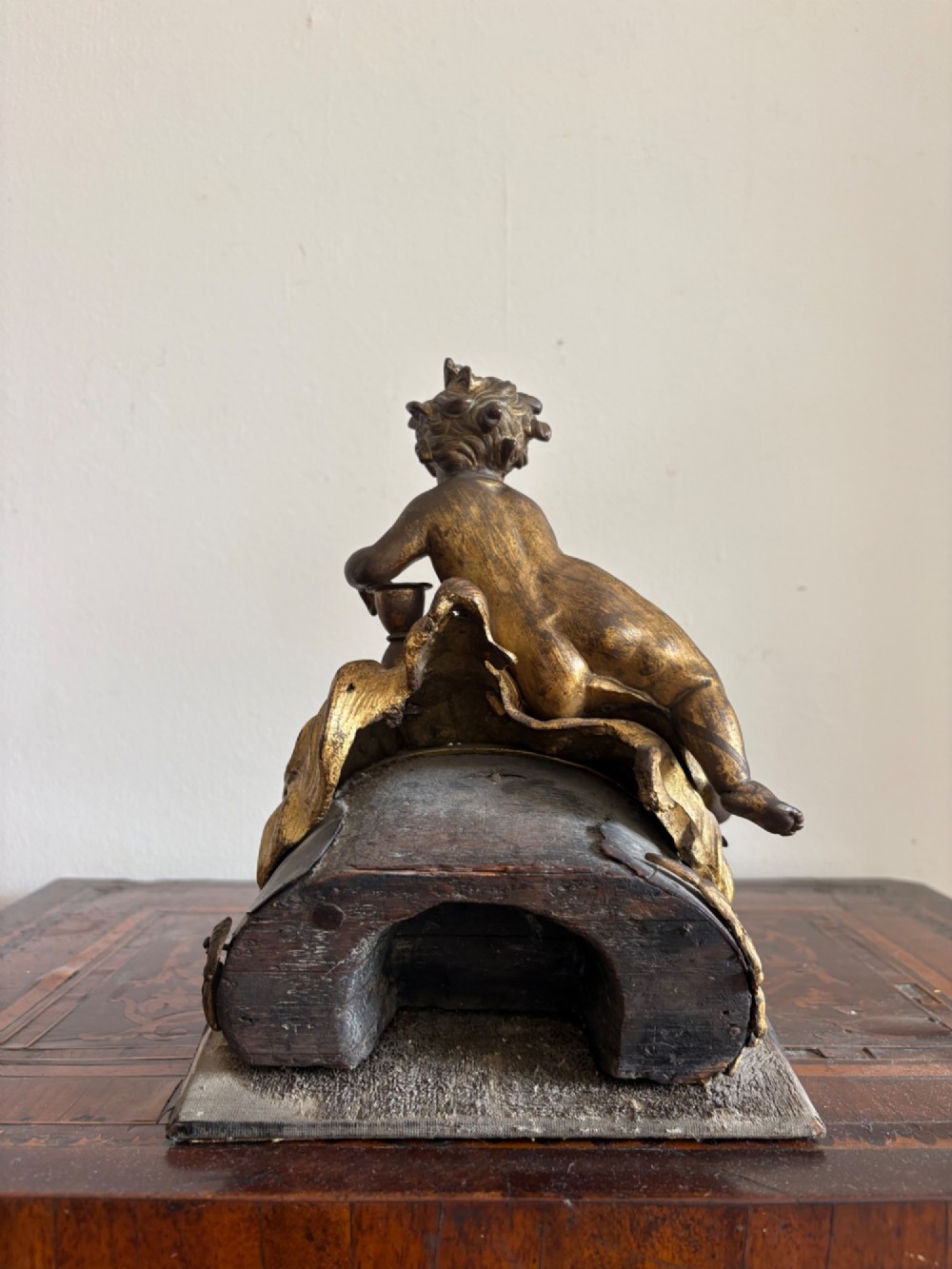 A late eighteenth or nineteenth-century French gilt bronze ormolu sculpture featuring a reclining putto holding a small vessel above a scrolled arch base. View VI