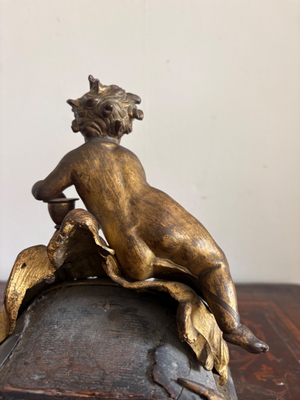 A late eighteenth or nineteenth-century French gilt bronze ormolu sculpture featuring a reclining putto holding a small vessel above a scrolled arch base. View VII