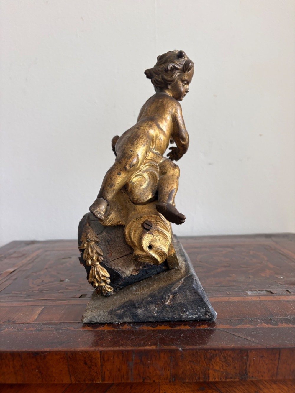 A late eighteenth or nineteenth-century French gilt bronze ormolu sculpture featuring a reclining putto holding a small vessel above a scrolled arch base. View VIII