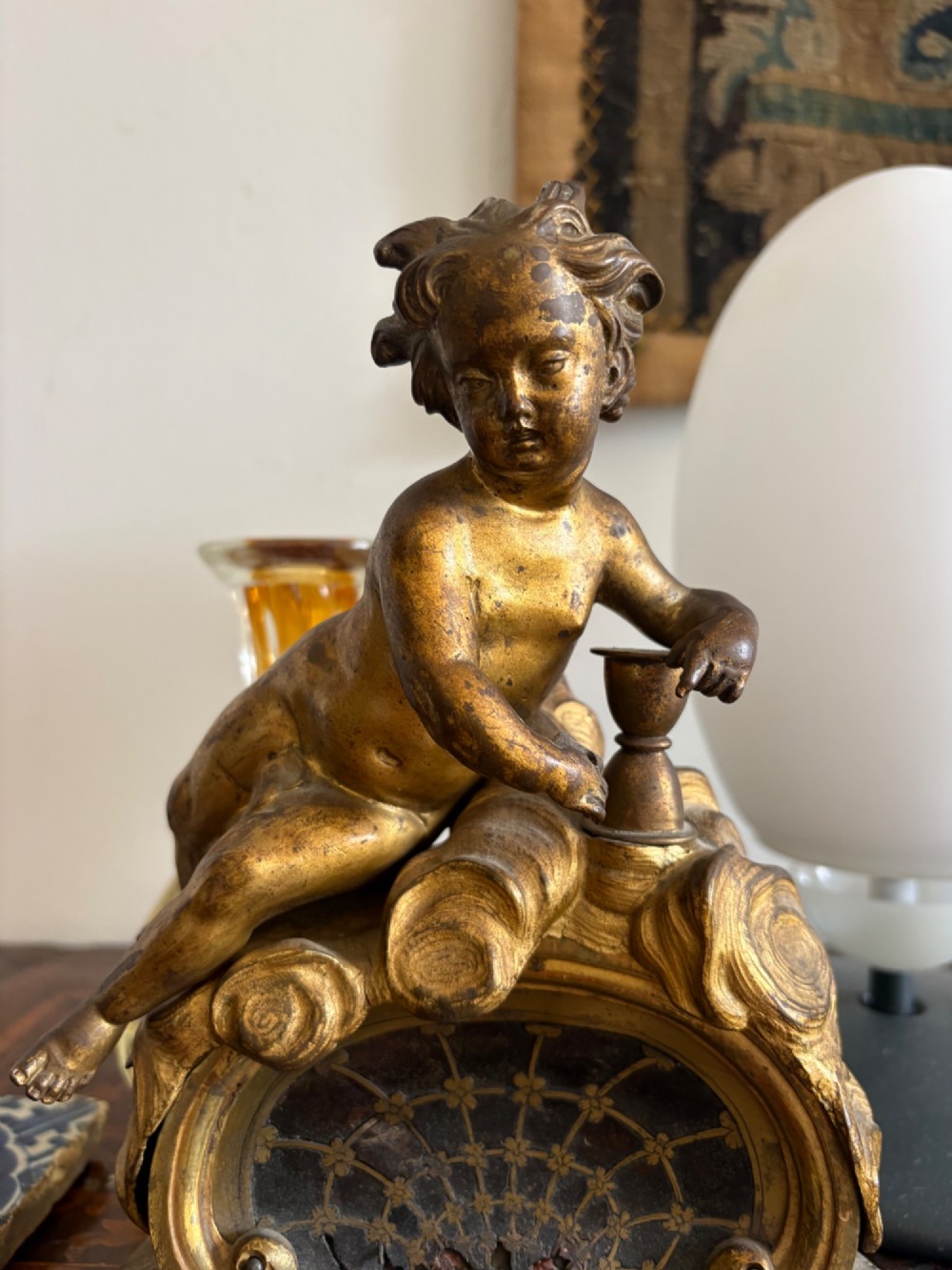 A late eighteenth or nineteenth-century French gilt bronze ormolu sculpture featuring a reclining putto holding a small vessel above a scrolled arch base. View IX