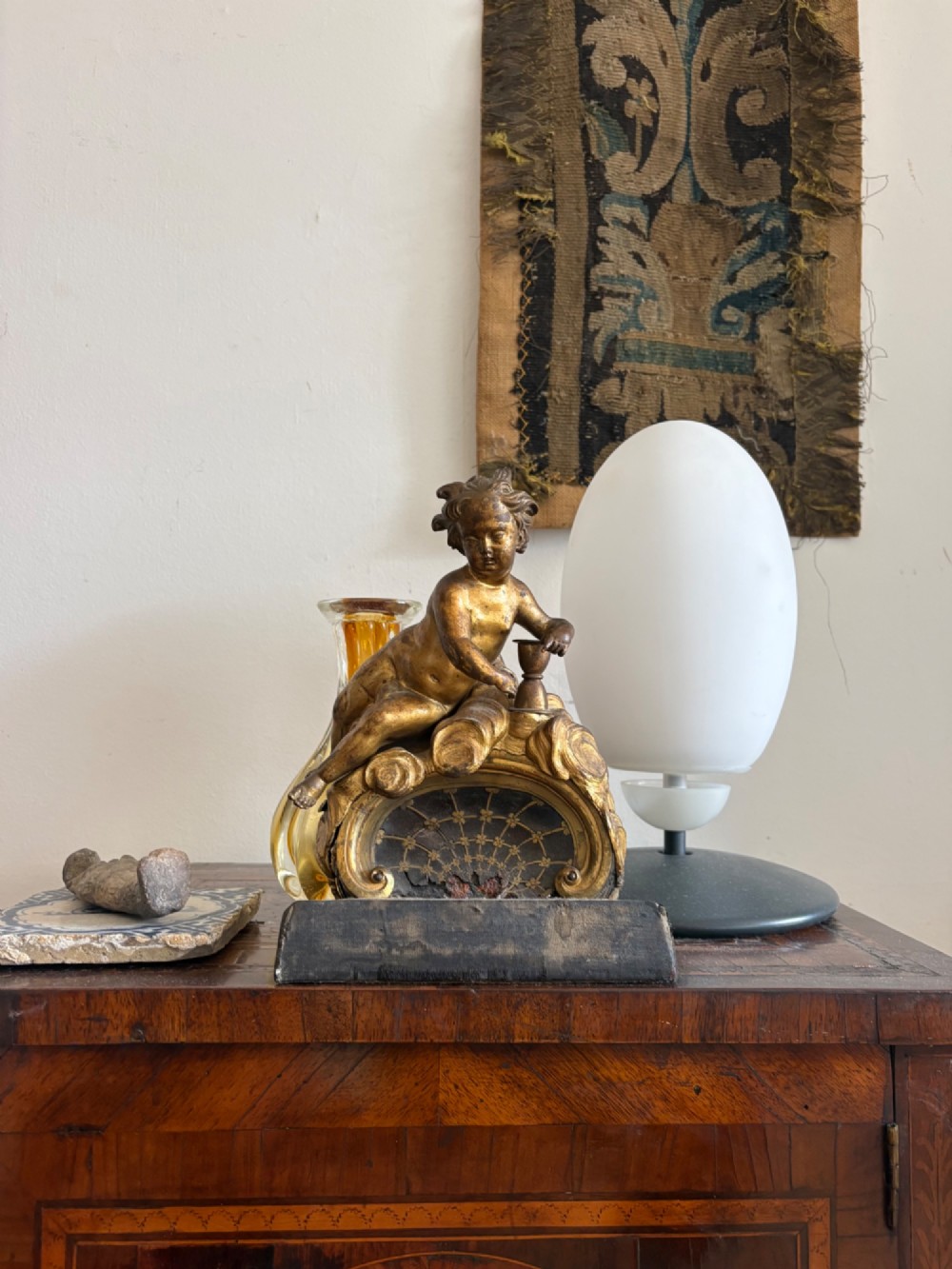 A late eighteenth or nineteenth-century French gilt bronze ormolu sculpture featuring a reclining putto holding a small vessel above a scrolled arch base. View X