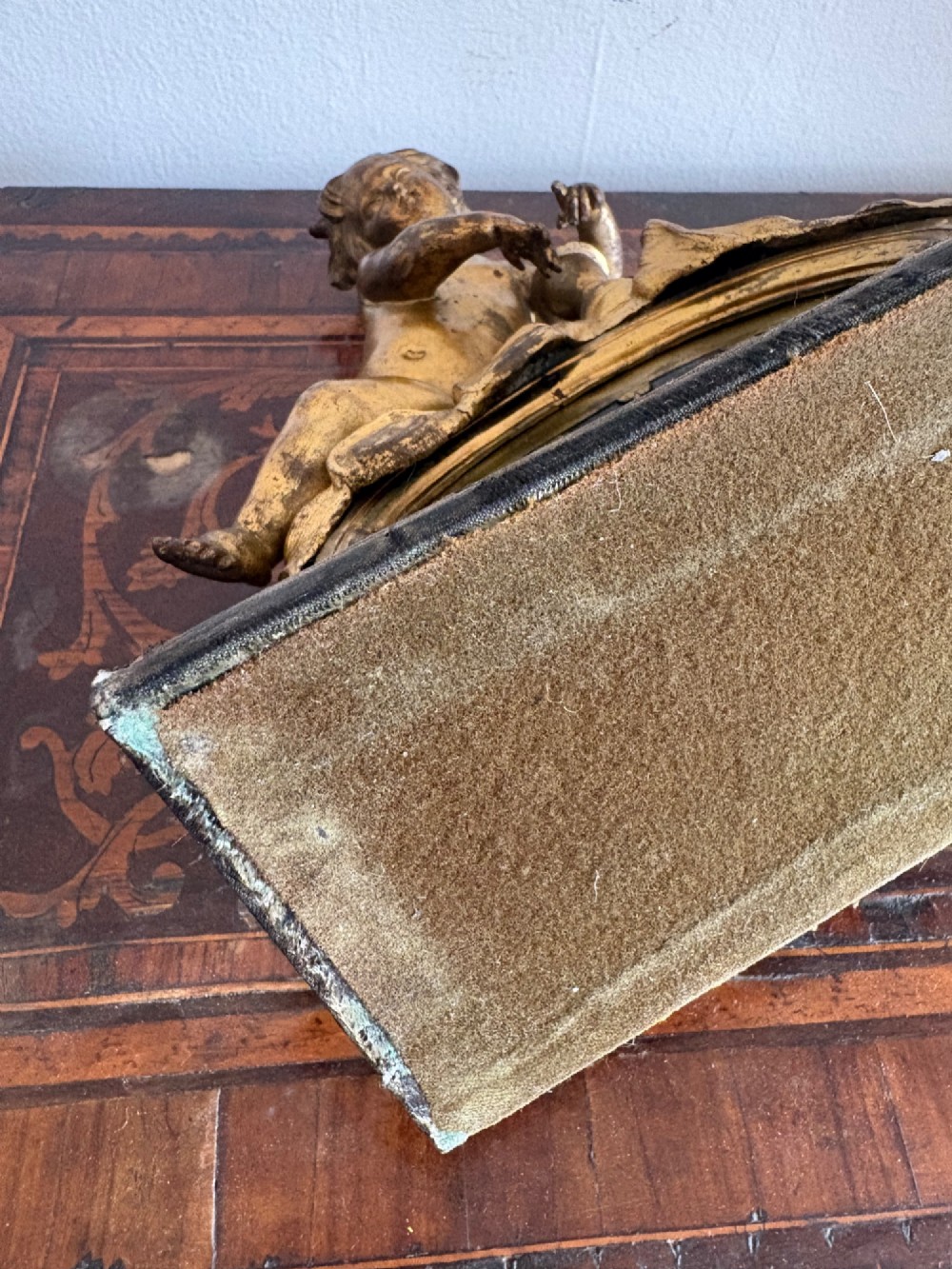 A late eighteenth or nineteenth-century French gilt bronze ormolu sculpture featuring a reclining putto holding a small vessel above a scrolled arch base. View XI