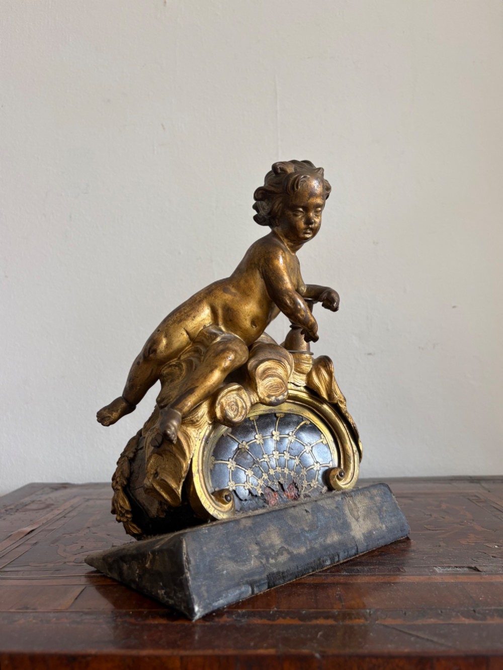 A late eighteenth or nineteenth-century French gilt bronze ormolu sculpture featuring a reclining putto holding a small vessel above a scrolled arch base. View XII
