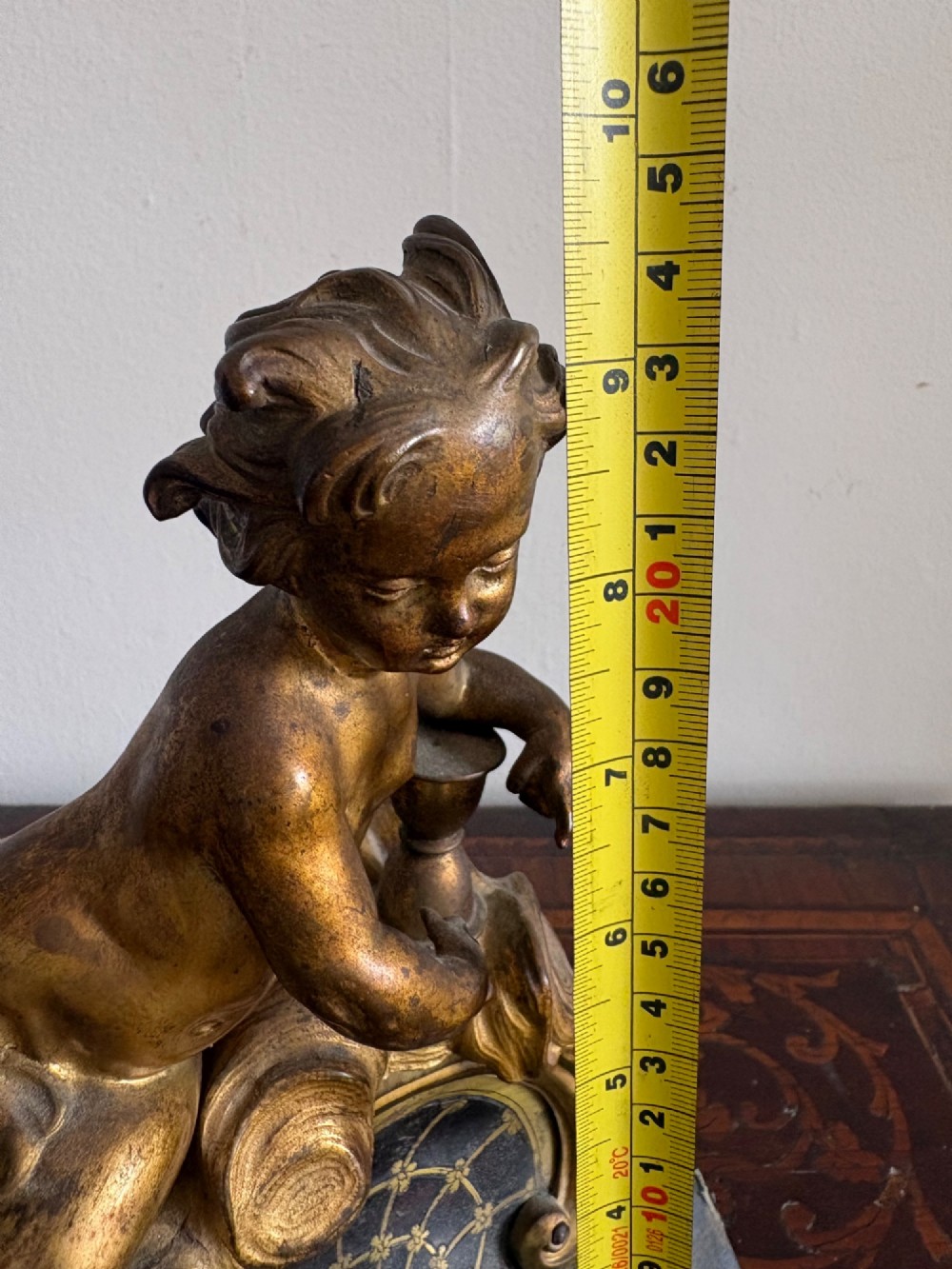 A late eighteenth or nineteenth-century French gilt bronze ormolu sculpture featuring a reclining putto holding a small vessel above a scrolled arch base. View XIV
