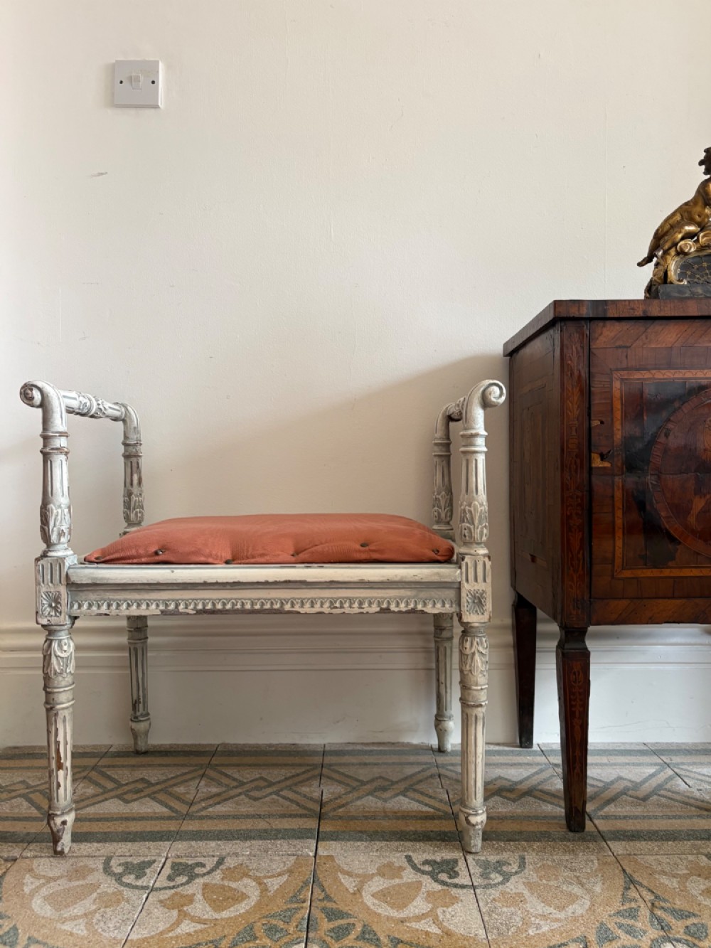 A white painted Gustavian style stool featuring raised side handles, fluted legs, and a terracotta silk upholstered seat. View III