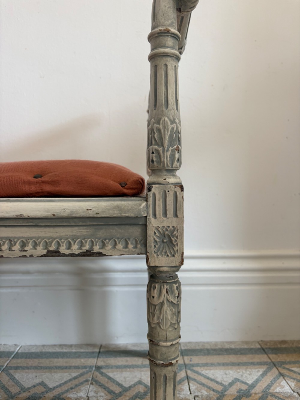 A white painted Gustavian style stool featuring raised side handles, fluted legs, and a terracotta silk upholstered seat. View IV