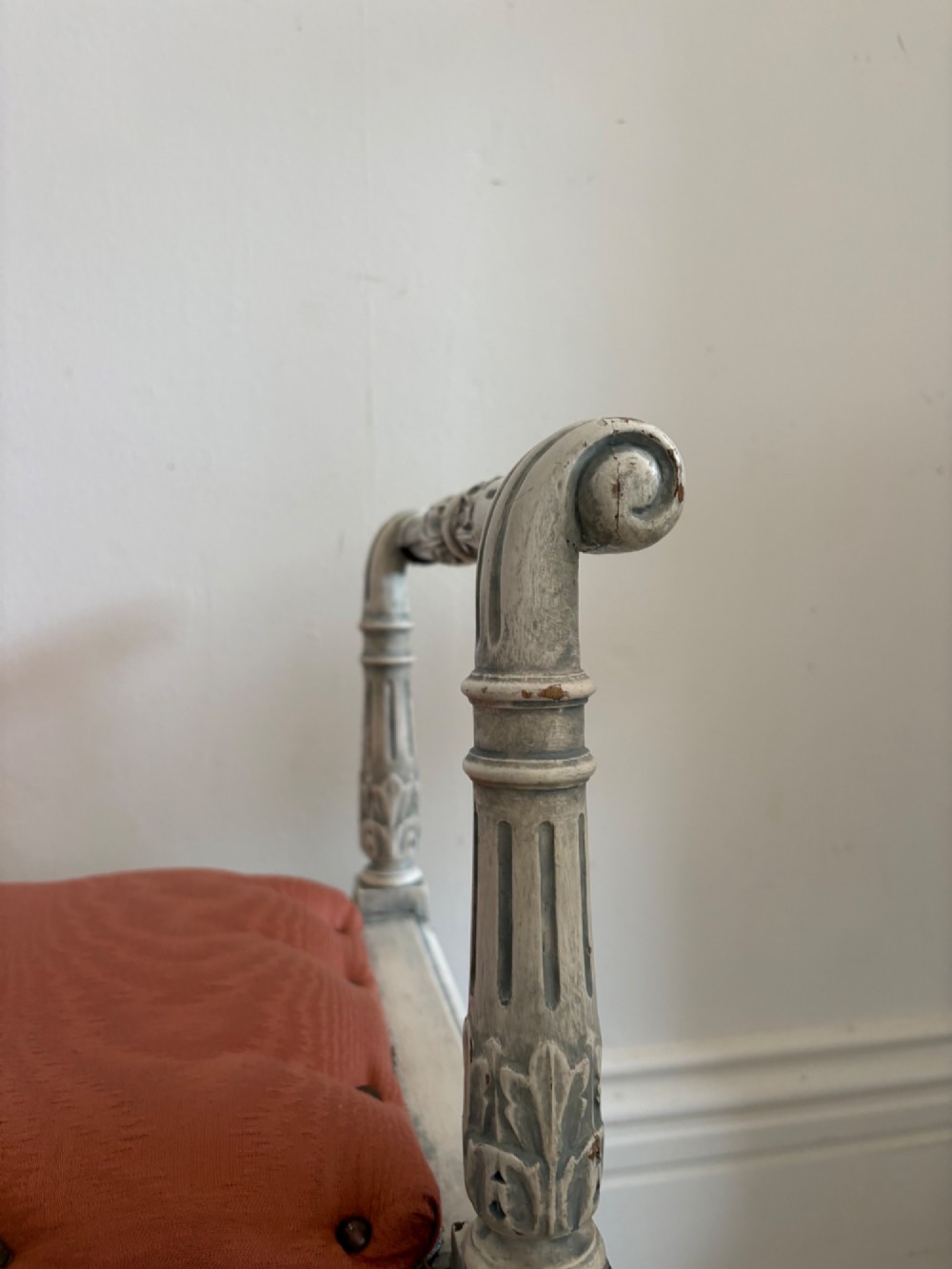 A white painted Gustavian style stool featuring raised side handles, fluted legs, and a terracotta silk upholstered seat. View V