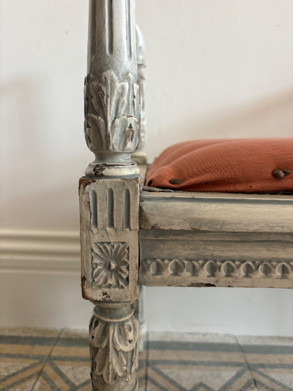 A white painted Gustavian style stool featuring raised side handles, fluted legs, and a terracotta silk upholstered seat. View VI