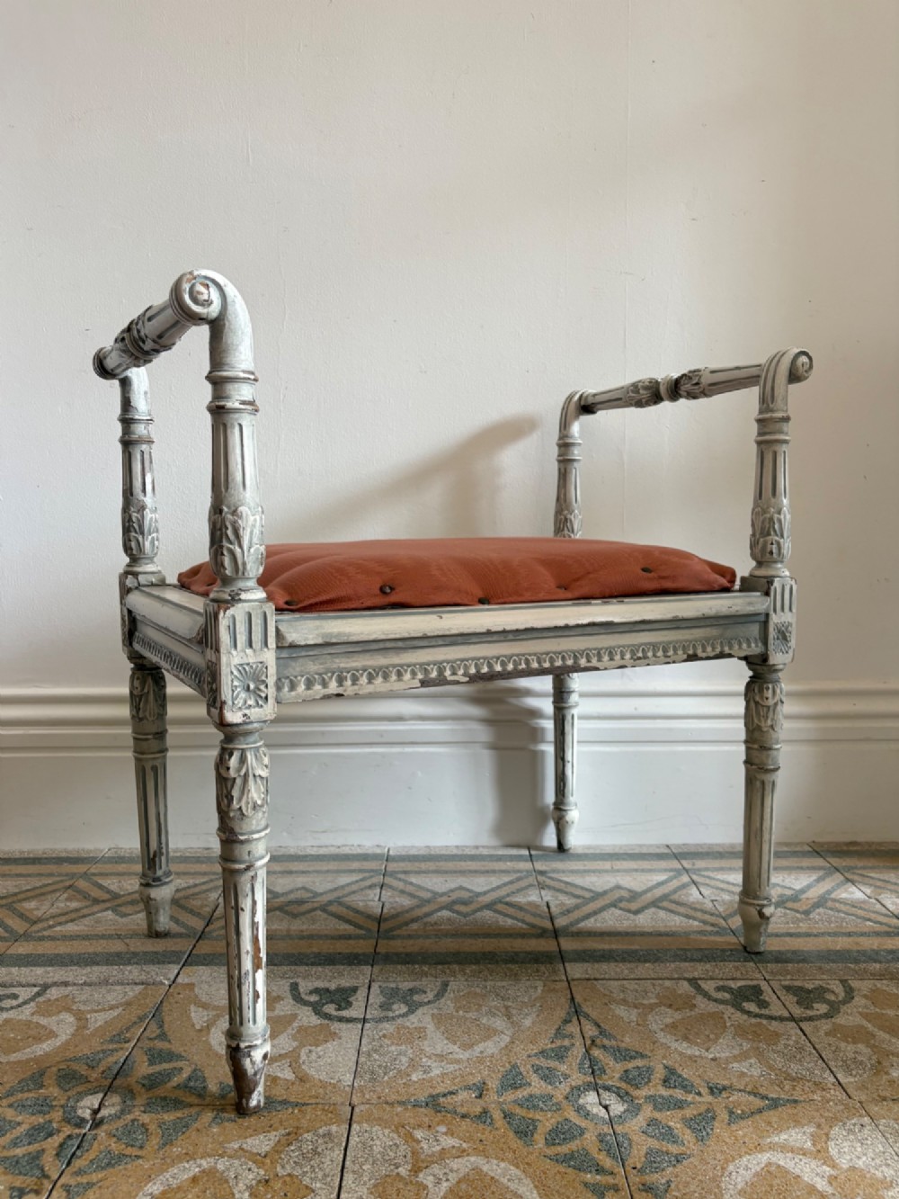 A white painted Gustavian style stool featuring raised side handles, fluted legs, and a terracotta silk upholstered seat. View VII
