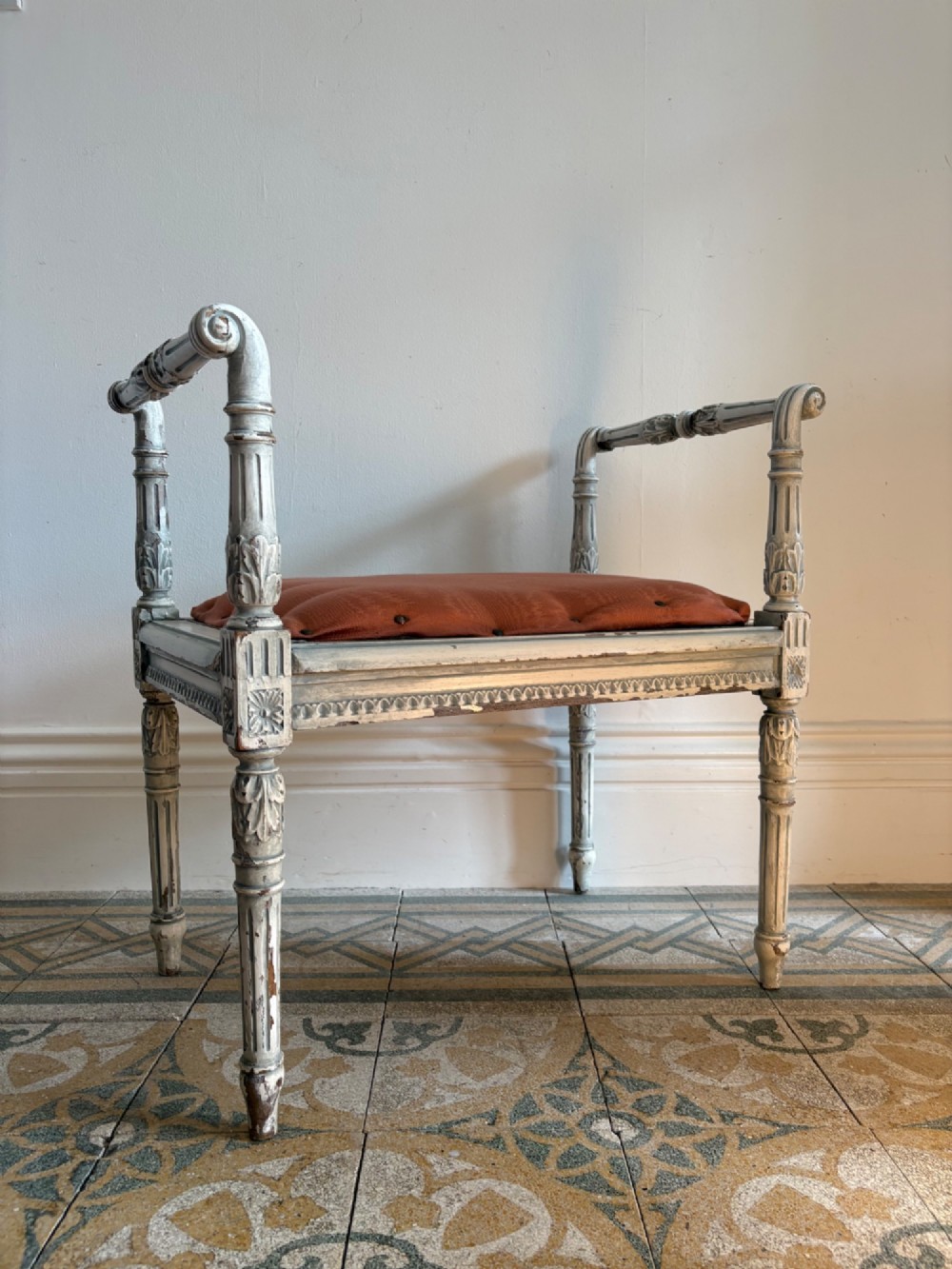 A white painted Gustavian style stool featuring raised side handles, fluted legs, and a terracotta silk upholstered seat. View VIII