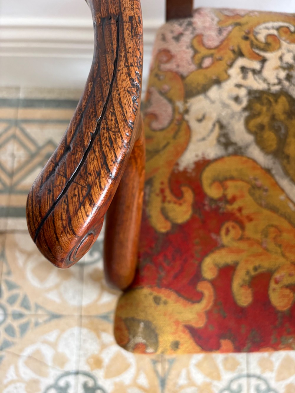 A George III elm ladderback open armchair featuring scrolled armrests and a patterned upholstered seat with fringed trim. View V